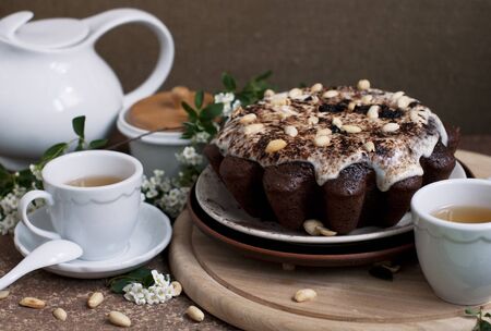Chocolate cake with peanuts on table with tea and flowersの写真素材