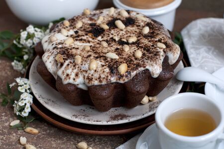 Chocolate cake with peanuts on table with tea and flowersの写真素材