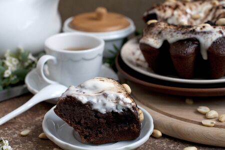 Chocolate cake with peanuts on table with tea and flowersの写真素材