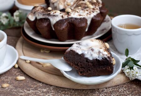 Chocolate cake with peanuts on table with tea and flowersの写真素材