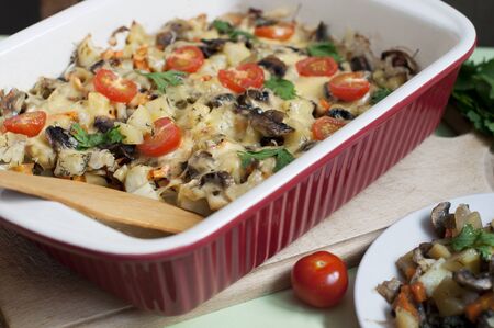 Baked potatoes, mushrooms and tomatoes with parsley and cheese on greenの写真素材