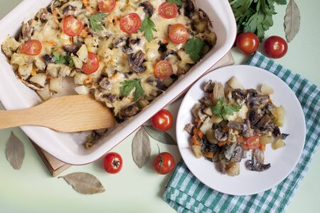 Baked potato, mushrooms and tomatoes with parsley and cheese on greenの写真素材