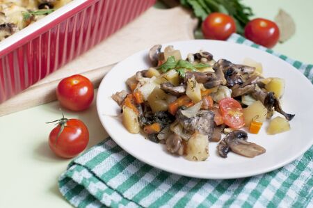 Baked potato, mushrooms and tomatoes with parsley and cheese on greenの写真素材