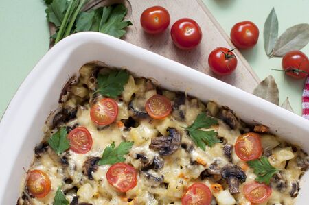 Baked potato, mushrooms and tomatoes with parsley and cheese on greenの写真素材