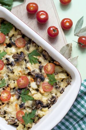 Baked potatoes, mushrooms and tomatoes with parsley and cheese on greenの写真素材