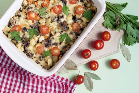 Baked potatos, mushrooms and tomatoes with parsley and cheese on dark brown background. Top viewの写真素材