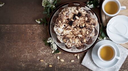 Chocolate cake with peanuts on table with tea and flowers on dark brown background. Top viewの写真素材