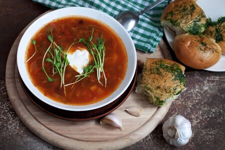 Red borsch with garlic pampusks, peas sprouts and garlic on dark brown background. Traditional dish of ukrainian cuisine. Top viewの写真素材
