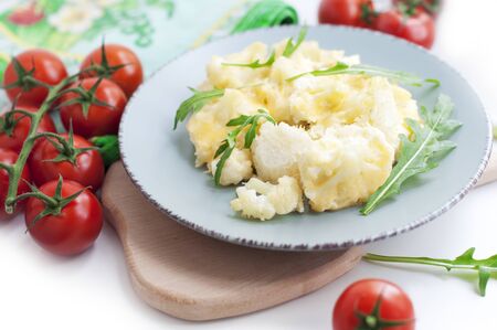 Baked cauliflower and tomatoes with cream-garlic sauce on whiteの写真素材