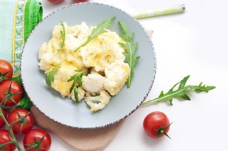 Baked cauliflower and tomatoes with cream-garlic sauce on whiteの写真素材