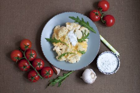 Baked cauliflower and tomatoes with cream-garlic sauce on dark brownの写真素材
