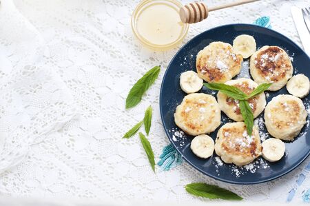 Cottage cheese pancakes, syrniki with banana and mint in blue plateの写真素材