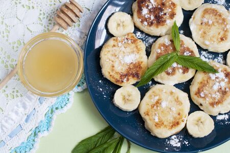 Cottage cheese pancakes, syrniki with banana and mint in blue plate. Top viewの写真素材