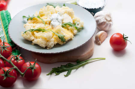 Baked cauliflower and tomatoes with cream-garlic sauce on white backgroundの写真素材