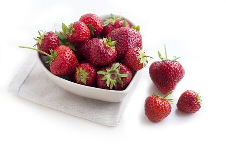 Breakfast with strawberries on white background. Breakfast for child. Strawberries in a white heart-shaped bowlの写真素材