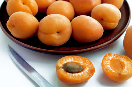 Ripe apricots in brown plate on white backgroundの写真素材