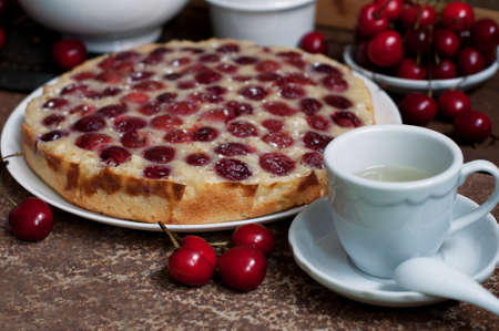 Tart with ripe sweet cherries and green tea on brown background. Homemade dessert with ripe sweet cherries.の写真素材