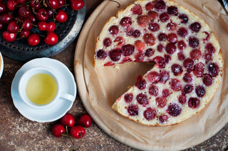 Tart with ripe sweet cherries and green tea on brown background. Homemade dessert with ripe sweet cherries. Top viewの写真素材