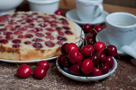 Tart with ripe sweet cherries and green tea on brown background. Homemade dessert with ripe sweet cherries.の写真素材