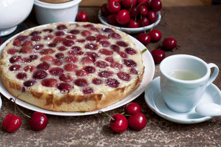 Tart with ripe sweet cherries and green tea on brown background. Homemade dessert with ripe sweet cherries.の写真素材