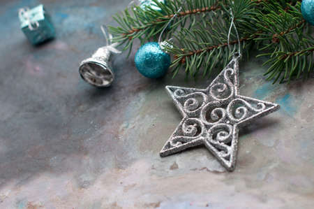 New Year and Christmas card with silver star, blue shine balls, bell, gift and fir branches on a gray background. A postcard with Christmas decorations.の写真素材