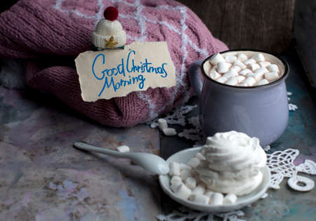 Christmas cup of cocoa with marshmelow greeting with a knit pink sweater on gray background. Cup of New Year's cocoa with marshmallows, knitted white snowflakes, sweets and Christmas decorationsの写真素材
