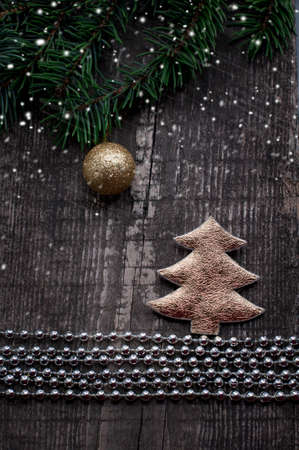 Christmas card with gold fir and gold ball on wooden background with falling snowの写真素材