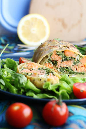 Strudel with salmon, spinach, cheese, arugula, lemon and tomatoes on blue backgroundの写真素材