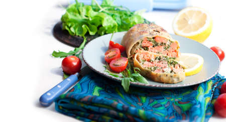 Strudel with salmon, spinach, cheese, arugula, lemon and tomatoes on white backgroundの写真素材