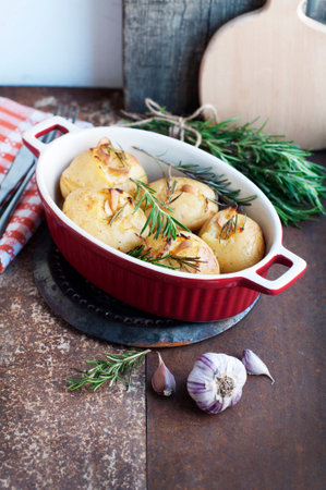 Rustic baked potatoes with rosemary and garlic on a light gray background. Traditional Portuguese cuisineの写真素材