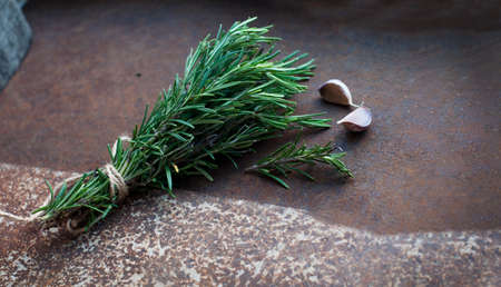 Bundle of rosemary with garlic on brown backgroundの写真素材