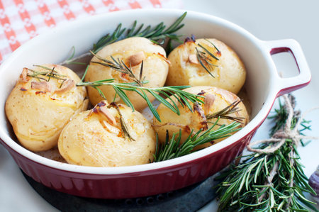 Rustic baked potatoes with rosemary and garlic on a light gray background. Traditional Portuguese cuisineの写真素材