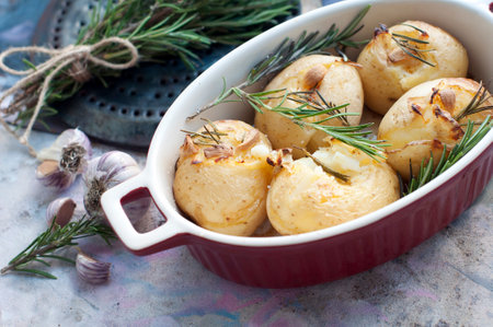 Rustic baked potatoes with rosemary and garlic on a light gray background. Traditional Portuguese cuisineの写真素材