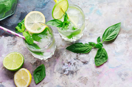 Glasses of basil lemonade with mint, basil, lime, lemon and ice on light gray background. Top viewの写真素材