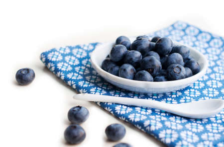 Blueberries on a white plate with a spoon on a white backgroundの写真素材