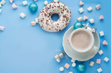 Christmas breakfast with white donuts, coffee and marshmallows with Christmas decorations on blue background. Top viewの写真素材