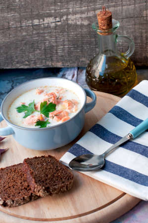 Creamy salmon soup Kalakeitto with salmon, carrot, parsley, onion, garlic, potatoes, dark bread and spoon on white background. Traditional Finnish hot soupの写真素材