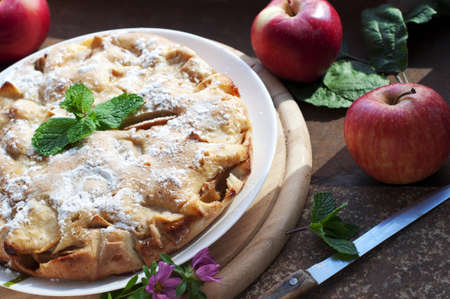 Apple homemade pie with red apples and flowers on dark brown background. Rustic styleの写真素材