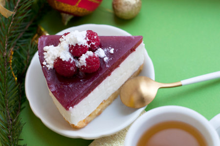 Christmas cheesecake with raspberries and cup of tea on green backgroundの写真素材