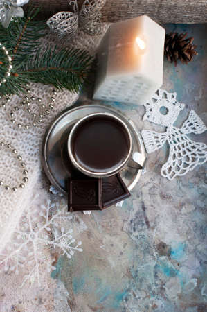Silver cup of coffee espresso with chocolate, candle, fir, knitted snowflakes, blue ball, silver decor, pine cones on gray background. New year coffee with christmas decorations. Top viewの写真素材