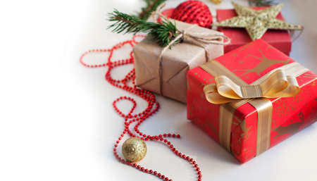 Boxes with gifts in red, gold and beige paper with ribbons, beads, star, spruce branch. Christmas gifts with New Year's decor on a white background. Place for text.の写真素材