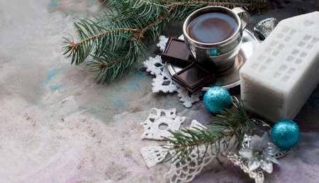 Silver cup of coffee espresso with chocolate, candle, fir, knitted snowflakes, blue ball, silver decor, pine cones on gray background. New year coffee with christmas decorations.の写真素材
