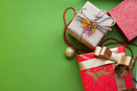 Boxes with gifts in red, gold and beige paper with ribbons, beads, spruce branch. Christmas gifts...