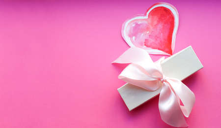 White box with gift, watercolor heart and light pink bow on pink background. Valentine's day gift. top view. Space for textの写真素材