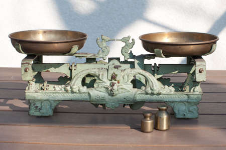 Antique vintage metal scales on with red apples, orange and weights on a wooden tableの写真素材