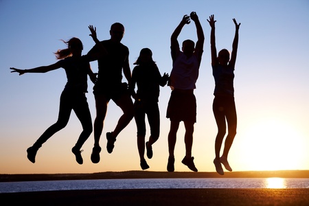 group of happy young people jumping at the beach on beautiful summer sunsetの写真素材