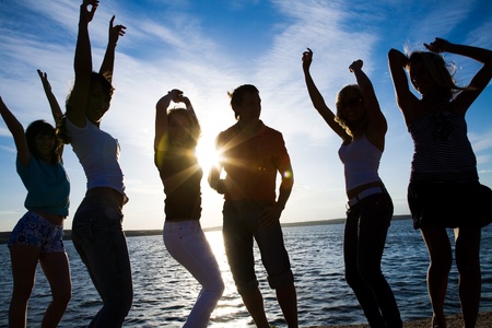 group of happy young people dancing at the beach on  beautiful summer sunsetの写真素材