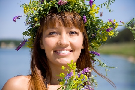 Portrait of Young beautiful woman wearing a wreath of wild flowers の写真素材