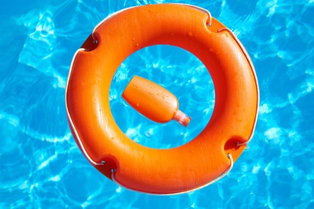 bright orange life buoy  floating on the surface of blue waterの写真素材