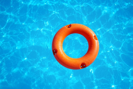 bright orange life buoy  floating on the surface of blue waterの写真素材